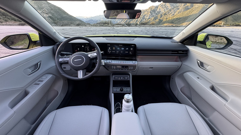 Stranski pogled na modri Q3, parkiran na zemlji pred travnatim hribom in modrim nebom