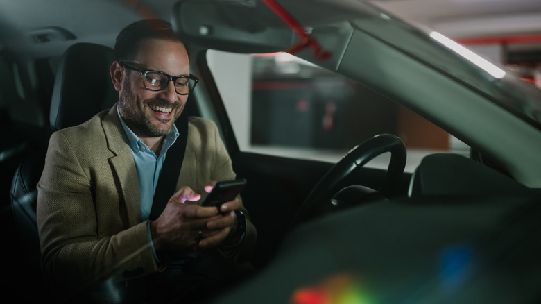 Moški, ki se v avtu igra s telefonom