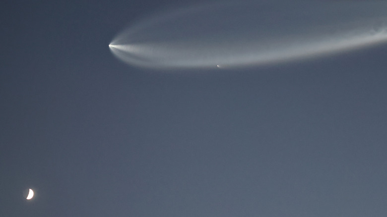 Raketa Falcon 9 izgine v atmosferi in za seboj pusti širok oblak nad polmesecem
