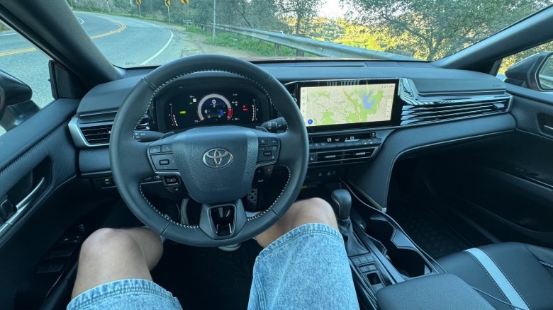 Fotografija iz mojega POV za volanom Camry Nightshade s travo in cesto, vidno skozi vetrobransko steklo