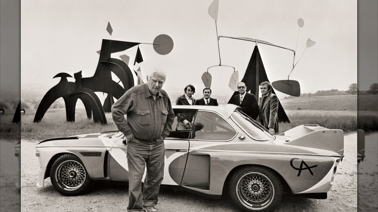 Kipar Alexander Calder stoji poleg BMW 3.0 CSL iz leta 1975, ki ga je naslikal, z nekaj njegovimi skulpturami v ozadju.