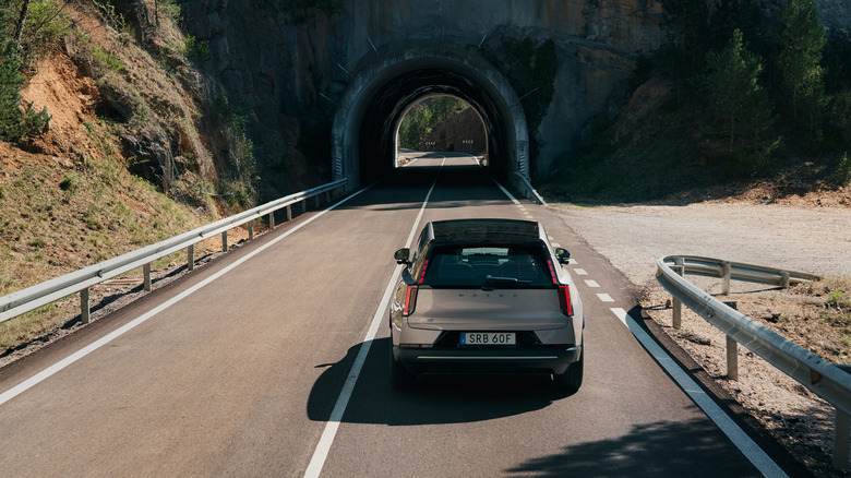 Srebrni Volvo EX60 2027, ki se približuje gorskemu tunelu