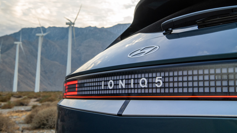 Zadnja slika Hyundai Ioniq 5 EV z vetrno elektrarno v ozadju.