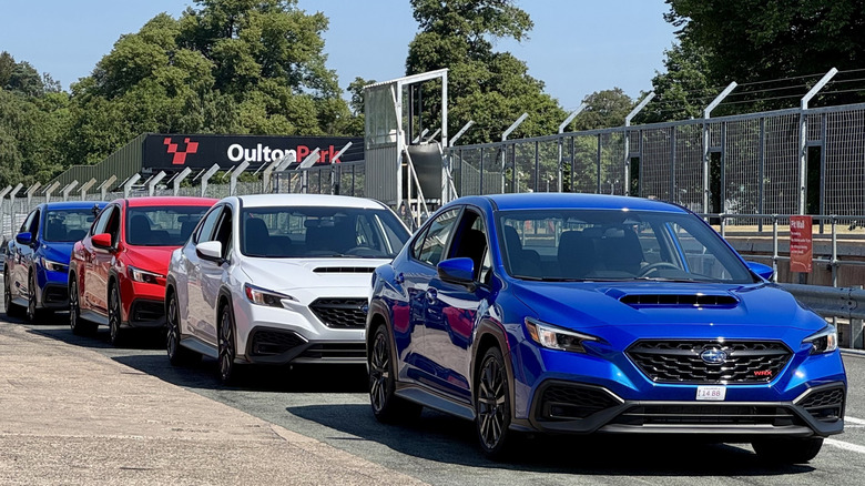 Fotografija štirih rdeče-belih in modrih WRX-ov, parkiranih v boksih v Oulton Parku