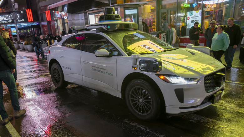 Vozilo Waymo se je ustavilo, okoli njega pa hodijo pešci