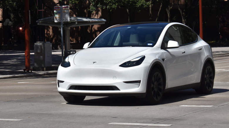 Pogled od spredaj 3/4 na belo Teslo Model Y 2024, ki se vozi po mestni ulici
