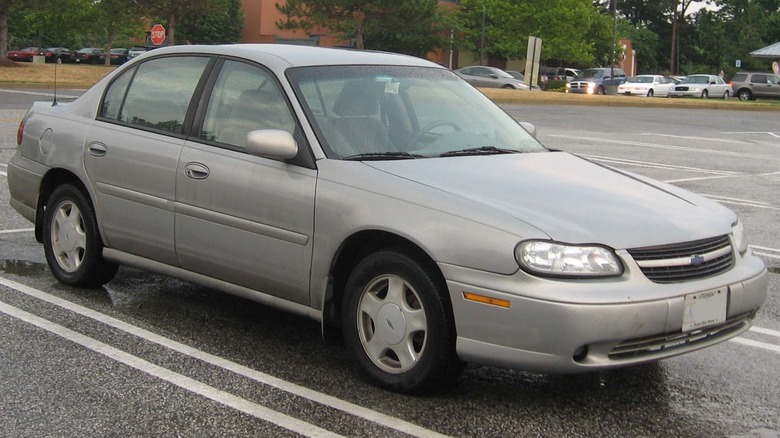 Chevrolet Malibu pete generacije brez duše v še bolj brezdušni srebrni barvi, na parkirišču.