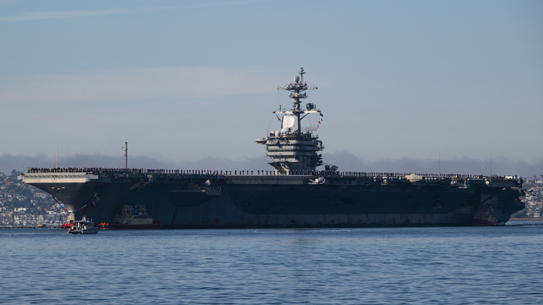 SAN DIEGO, KALIFORNIJA – 20. DECEMBER: Mornarji in marinci vodijo letalonosilko ameriške mornarice razreda Nimitz USS Abraham Lincoln (CVN 72), ki jo vodijo vlačilci v zalivu San Diego, ko se vrača v matično pristanišče Naval Air Station North Island po 5-mesečni napotitvi na Bližnji vzhod 20. decembra 2024 v San Diegu. Diego, Kalifornija. (Fotografija Kevina Carterja/Getty Images)
