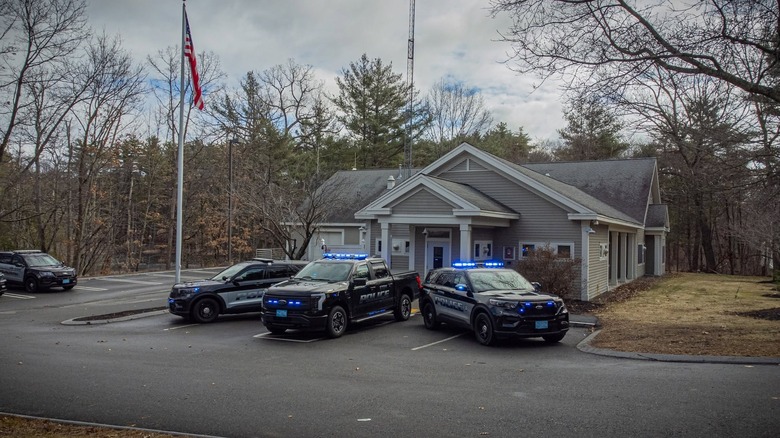 Trije policijski avtomobili z utripajočimi lučmi parkirani pred policijsko postajo Stow v Massachusettsu