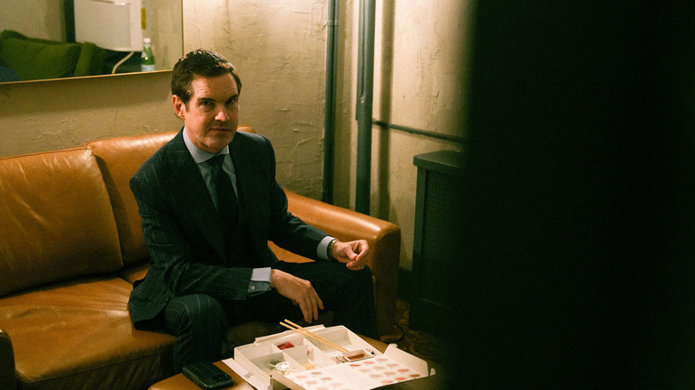 Jimmy Carr sedi na kavču in jé suši
