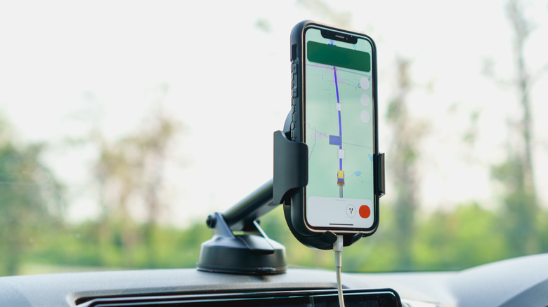 Telefon, ki prikazuje navigacijsko aplikacijo v držalu, nameščenem na armaturno ploščo avtomobila