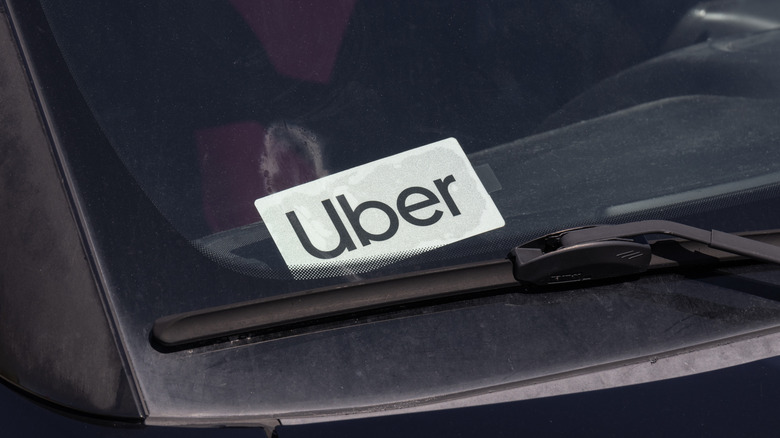 Bližnji posnetek nalepke Uber na vetrobranskem steklu.