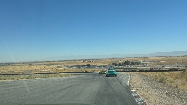Širok posnetek s sovoznikovega sedeža, ki prikazuje turkiznega M3, ki sledi rumenemu označevalcu, s širokim pogledom na Willow Springs in puščavo ter jasnim modrim nebom