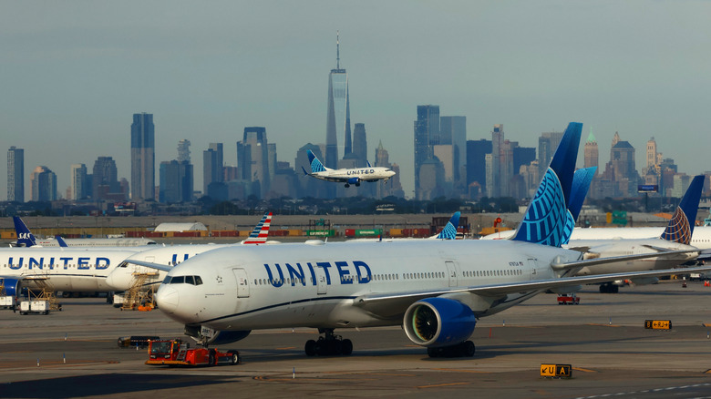 Letalo United Airlines pristane na mednarodnem letališču Newark Liberty pred obzorjem spodnjega dela Manhattna in One World Trade Center 8. avgusta 2026, gledano iz Newarka v New Jerseyju.