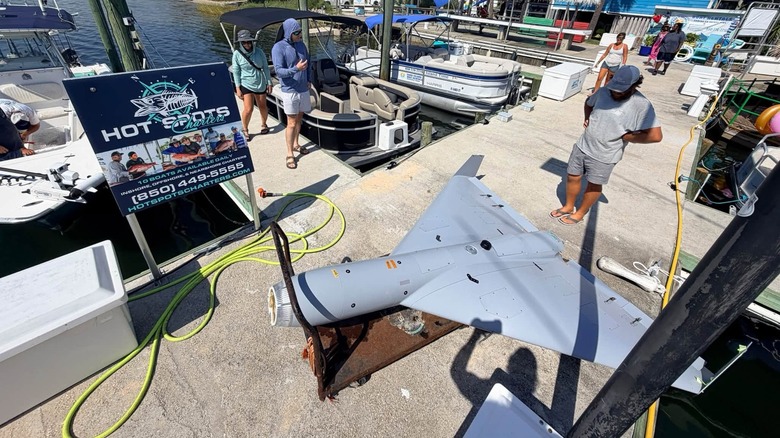 Poškodovani dron LUCAS, ki sedi na pomolu poleg znaka Hot Spots Charters