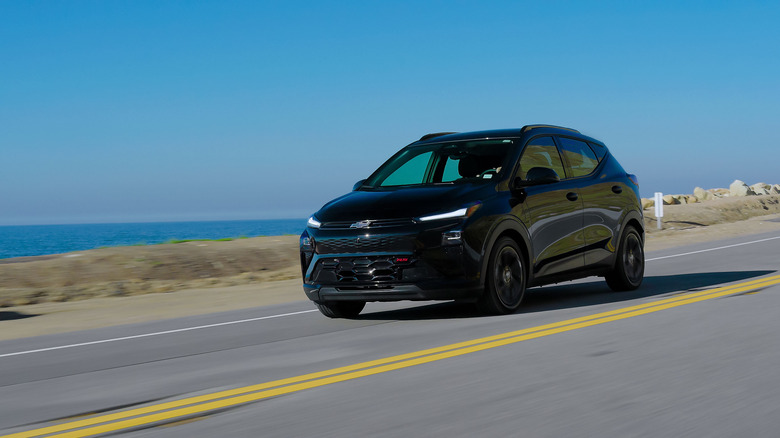 Pogled od spredaj 3/4 na črni Chevrolet Bolt 2027 v gibanju.