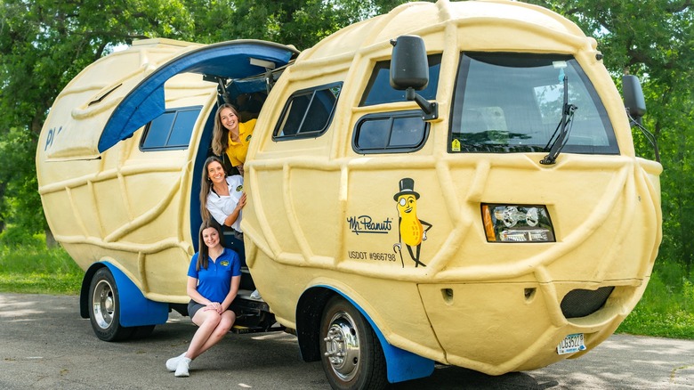 NUTmobile z odprtimi stranskimi vrati in tremi trenutnimi Peanutterji, ki sedijo na stopnicah v kabino