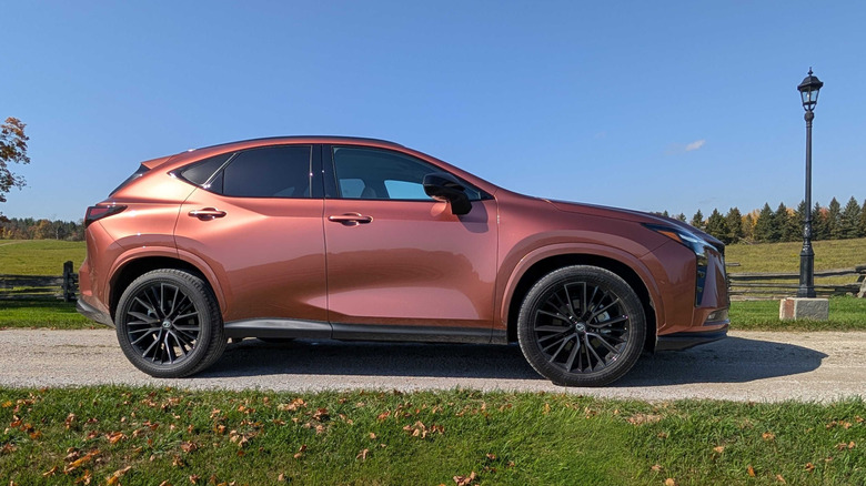 Stranski pogled na bakreni Lexus NX letnik 2027, parkiran na podeželskem dovozu v Ontariu.