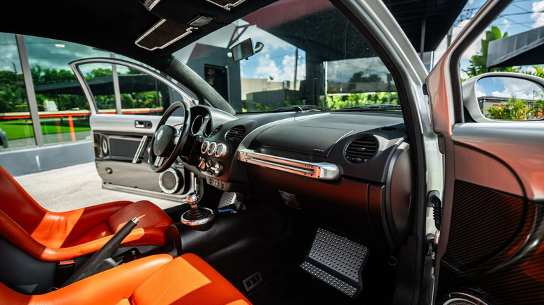 pogled skozi sovoznikova vrata na brezhibno in lepo notranjost Beetla RSi z oranžnimi sedeži in izpostavljenimi okrasnimi elementi iz karbona in aluminija